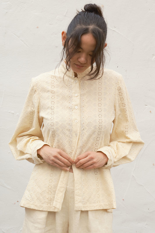 Woman wearing a cream-colored embroidered top and pants against a white background