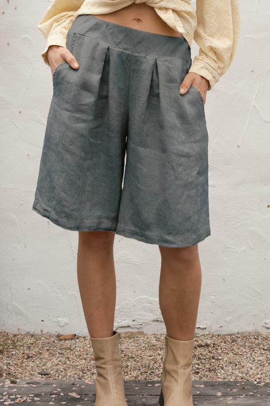 woman wearing gray full short standing by a white wall