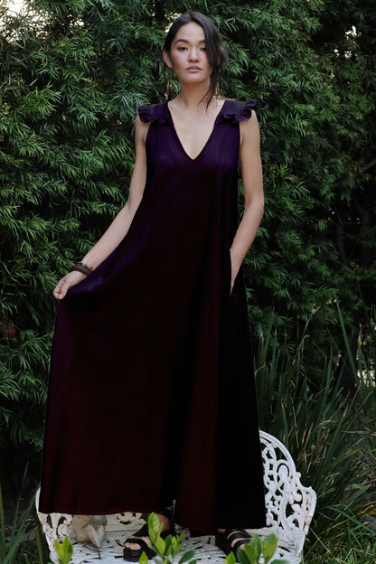 Woman in a black dress standing outdoors with greenery in the background