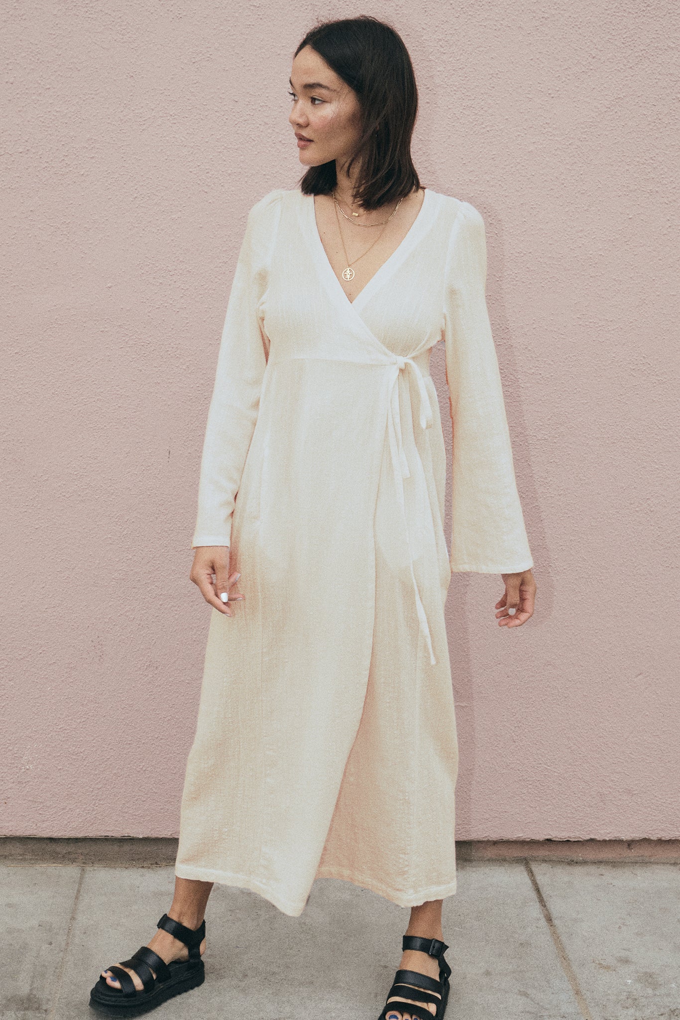 Woman wearing a white dress against a pink wall