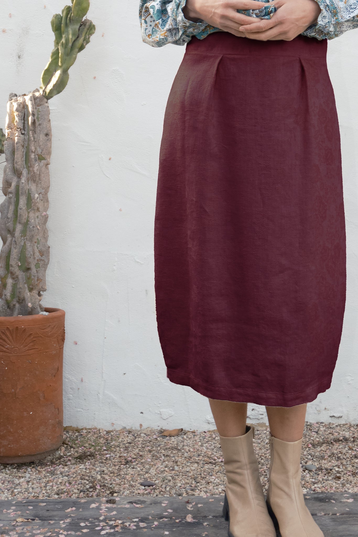 Person wearing a burgundy skirt with a cactus plant in the background
