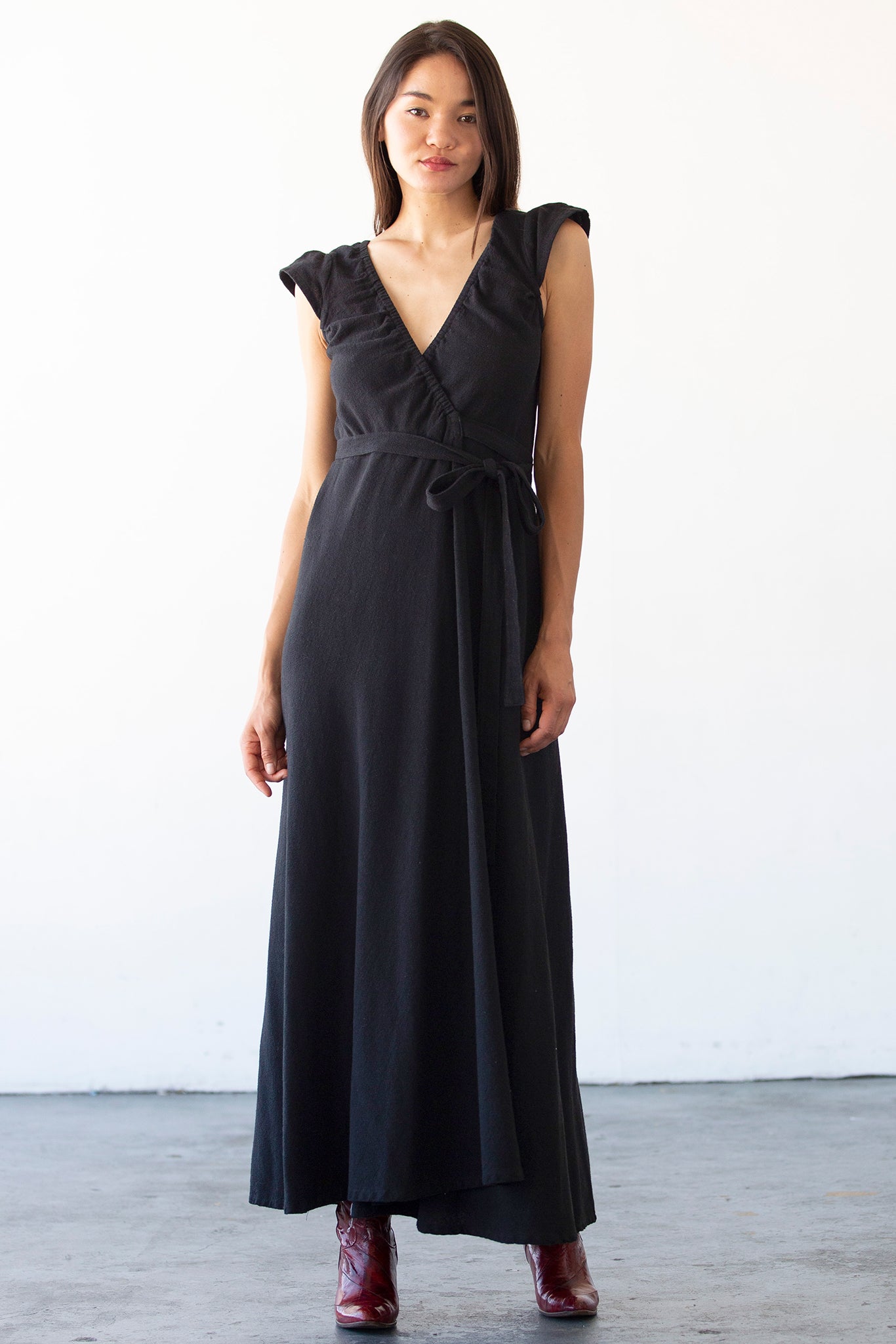 Woman wearing a black dress with ruffled shoulders against a white background