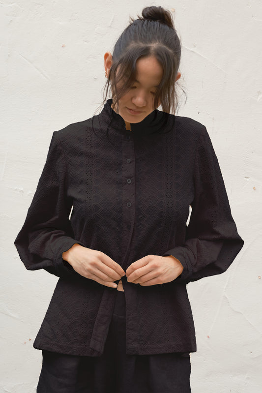Person wearing a black blouse against a white background