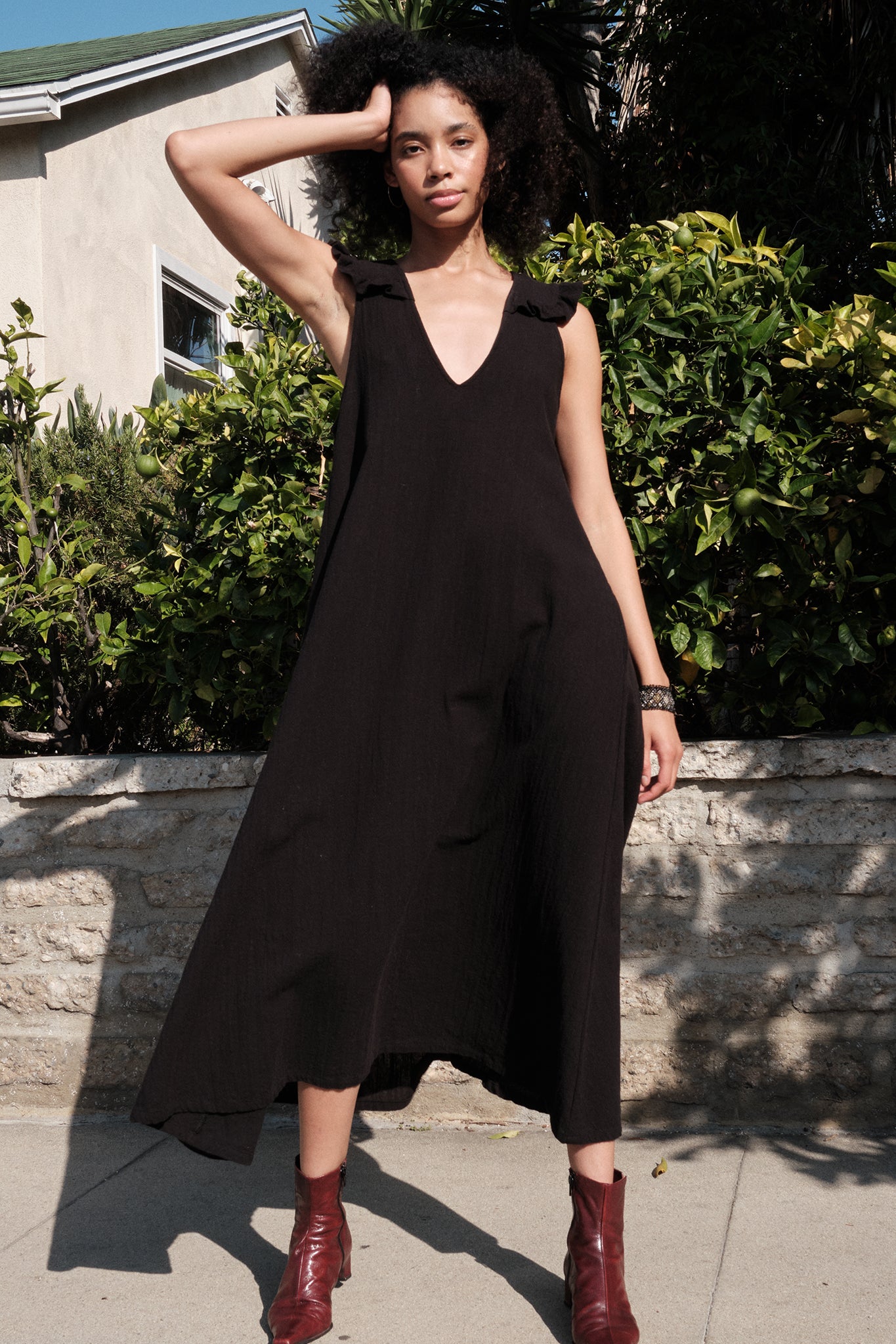 Woman wearing a black sleeveless dress with a deep neckline, standing outdoors.