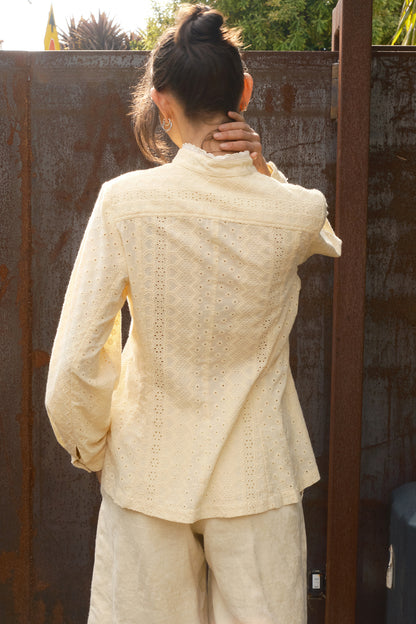Person wearing a beige jacket and pants standing against a wooden fence. back view 