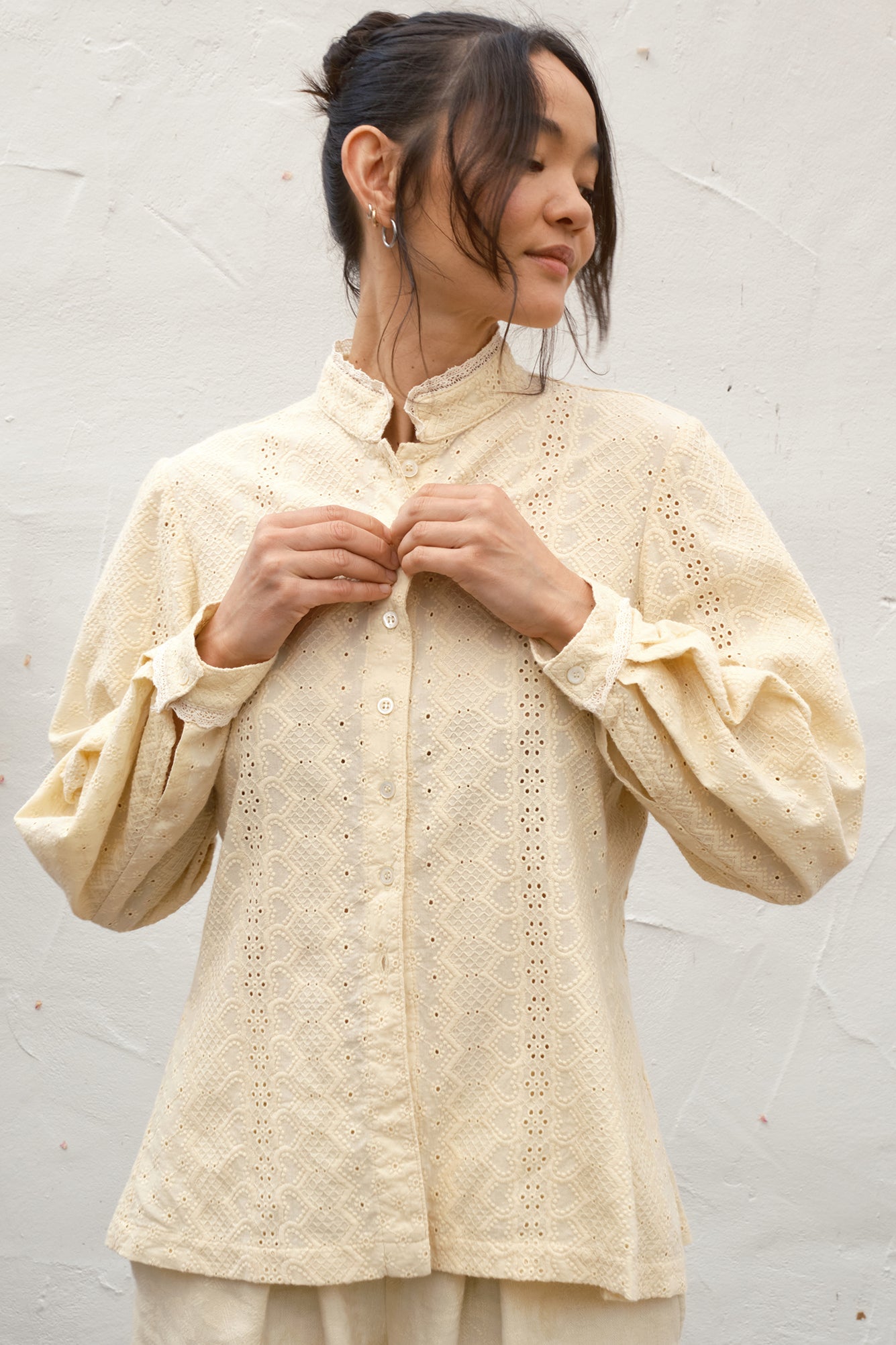 Woman wearing a beige embroidered blouse against a light background