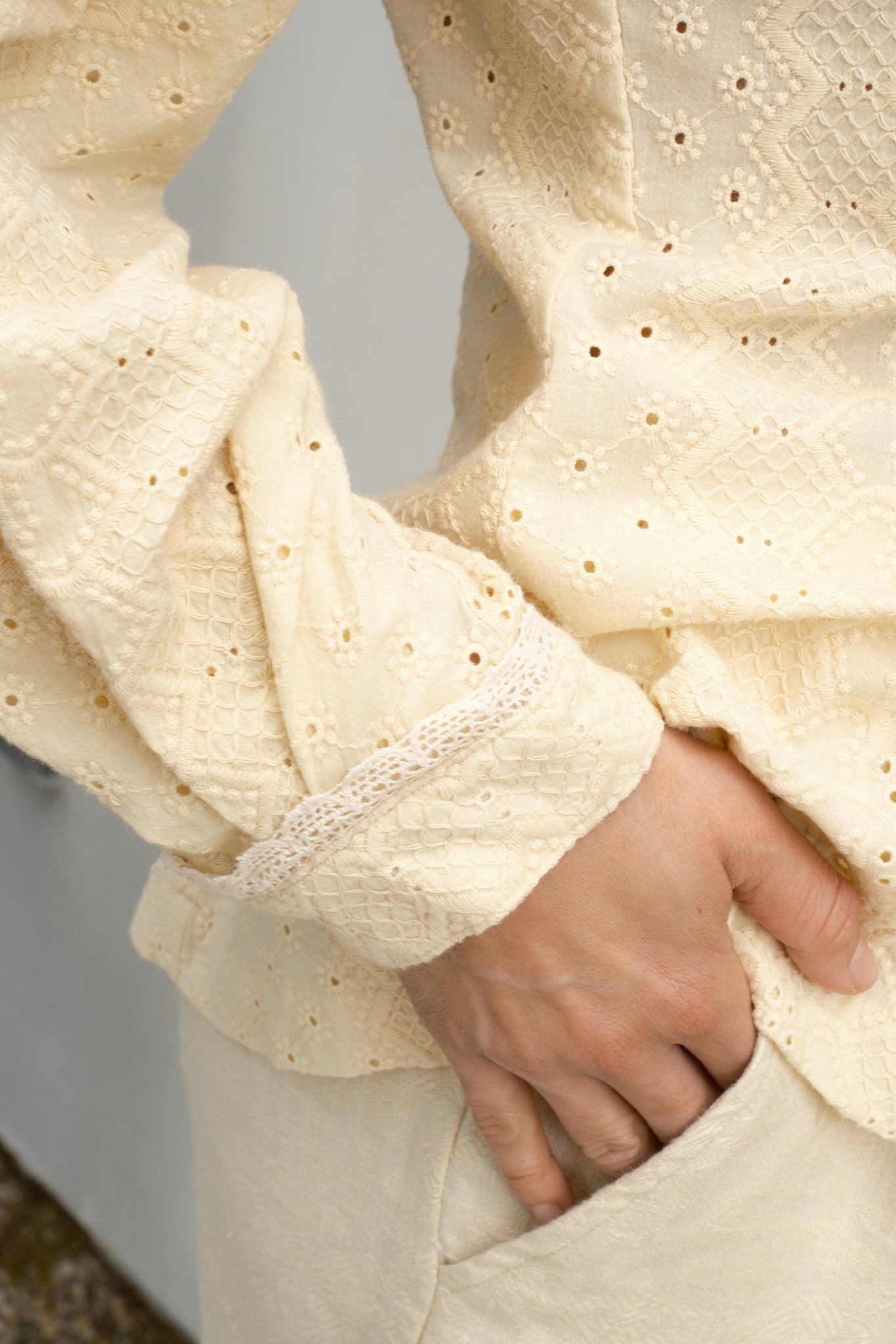 Close-up of a person wearing a textured cream blouse with sleeve detail with a blurred background