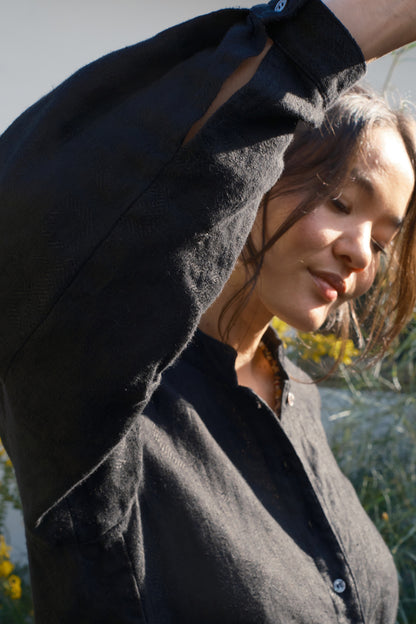 Woman wearing a black coat with a blurred natural background. sleeve detail