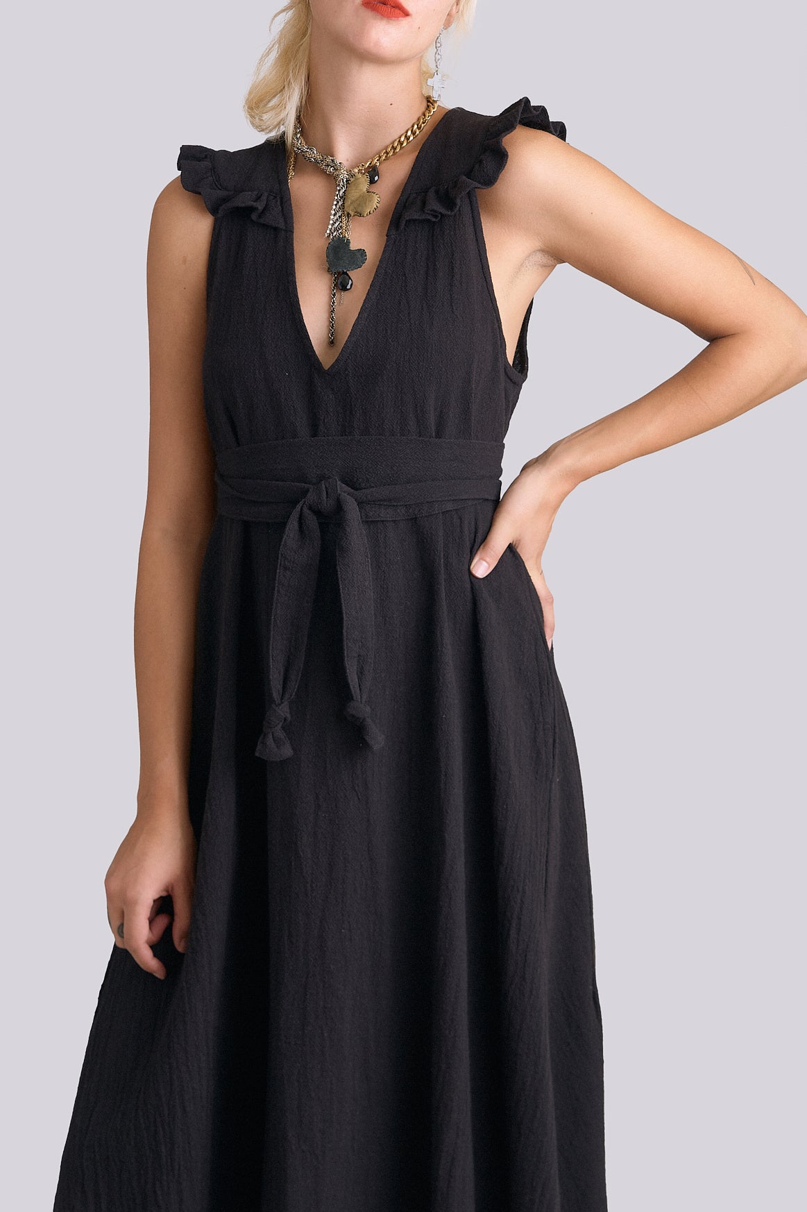 Black dress with ruffled sleeves worn by a model on a light gray background