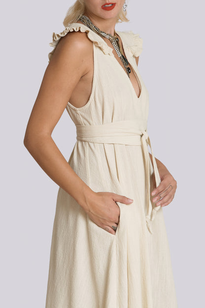Woman wearing a beige sleeveless dress with a belt on a plain background