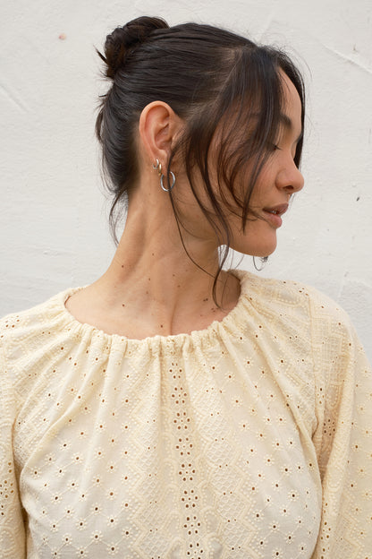 Woman wearing a beige blouse with a textured pattern against a white background