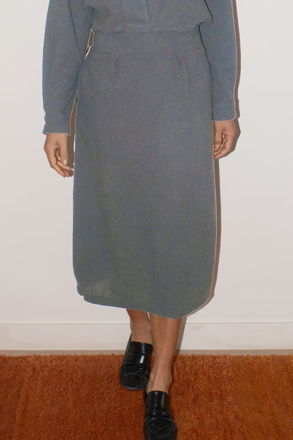 Person wearing a gray skirt with a white wall background