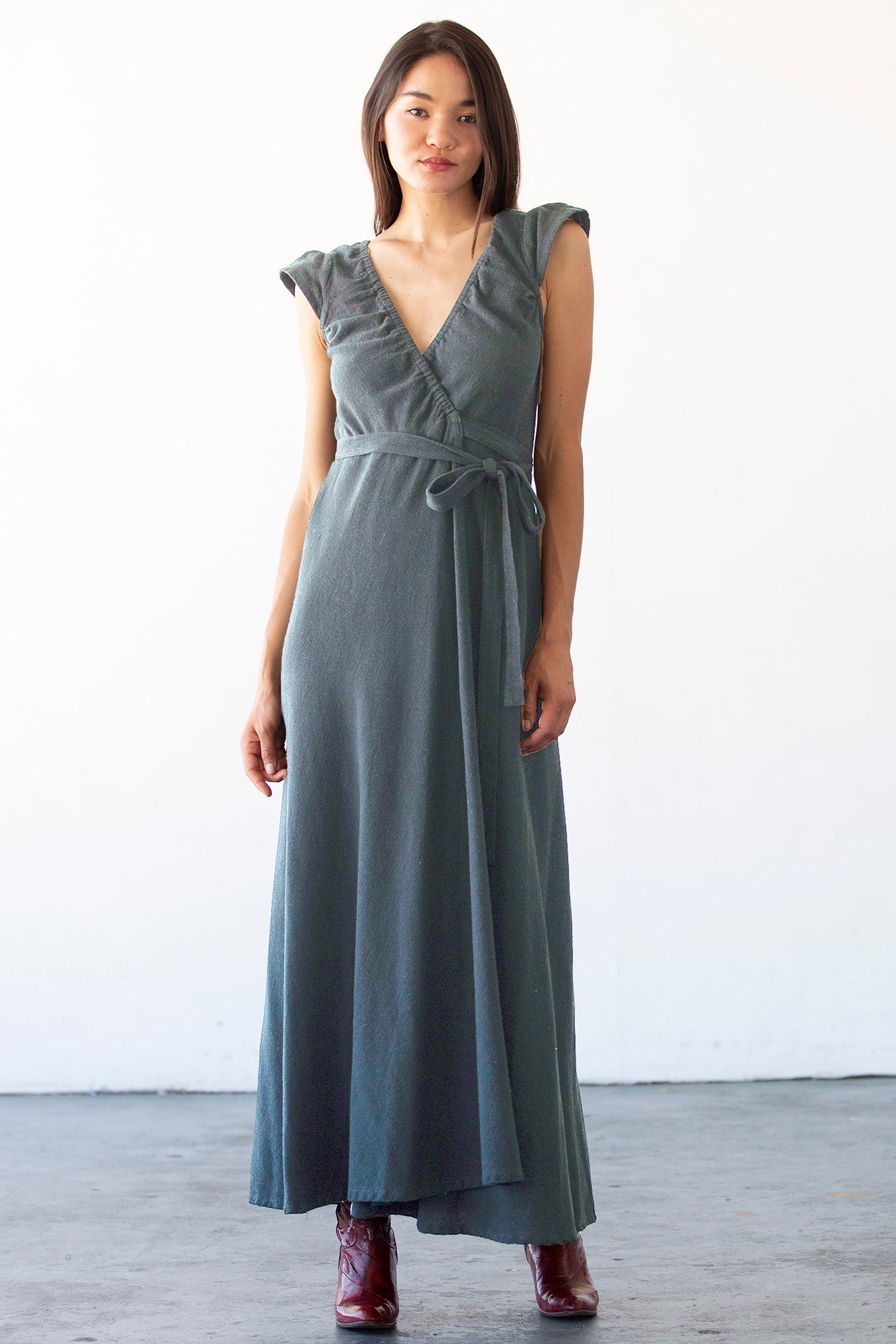 Woman wearing a long gray dress against a white background