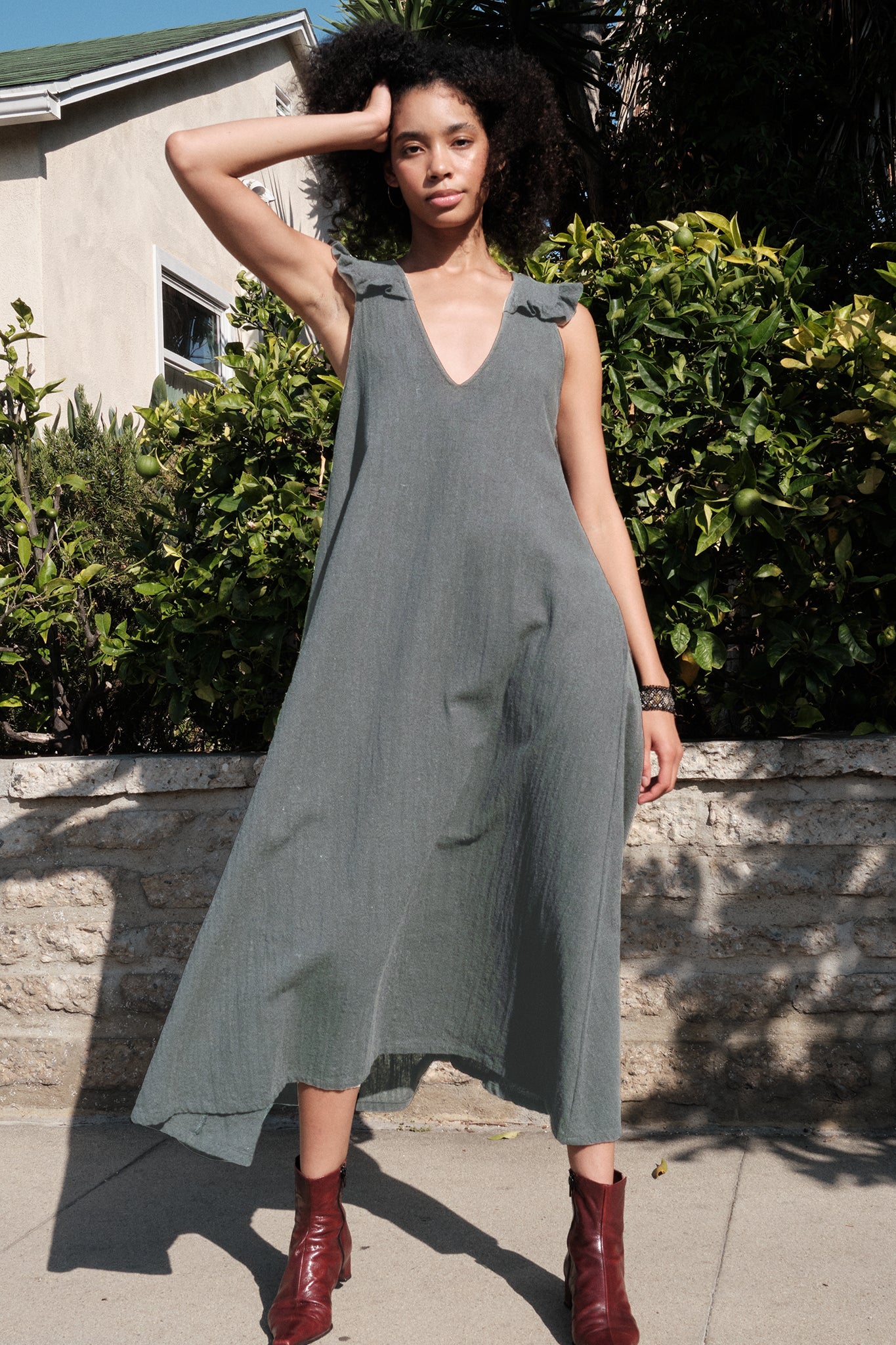 Woman wearing a gray dress with ruffled sleeves in an outdoor setting.