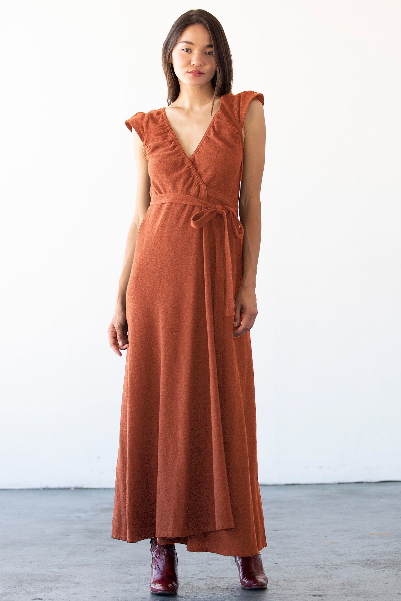 Woman wearing a persimmon colored dress against a white background